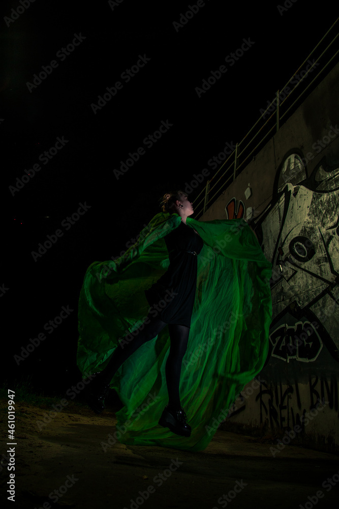 Naklejka premium Girl posing in green draping on dark background