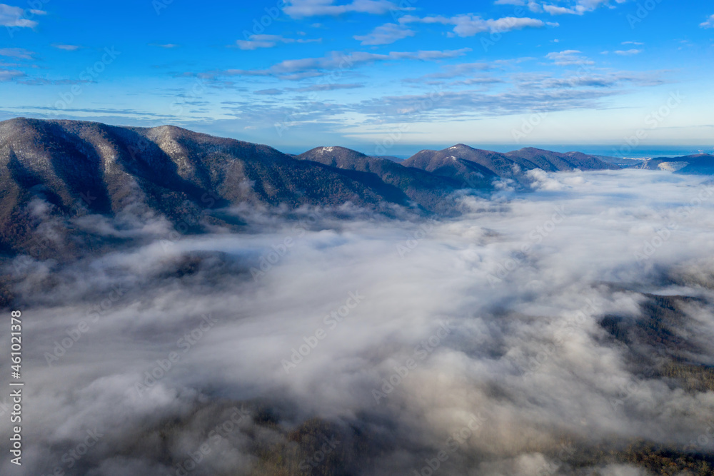 Drone view of the fog above mountain forest on sunny winter day. Gelendzhik, Krasnodar Krai, Russia.