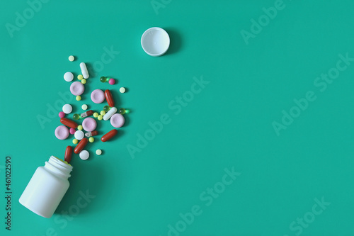 Assorted medical tablets scattered from a jar on a blue background