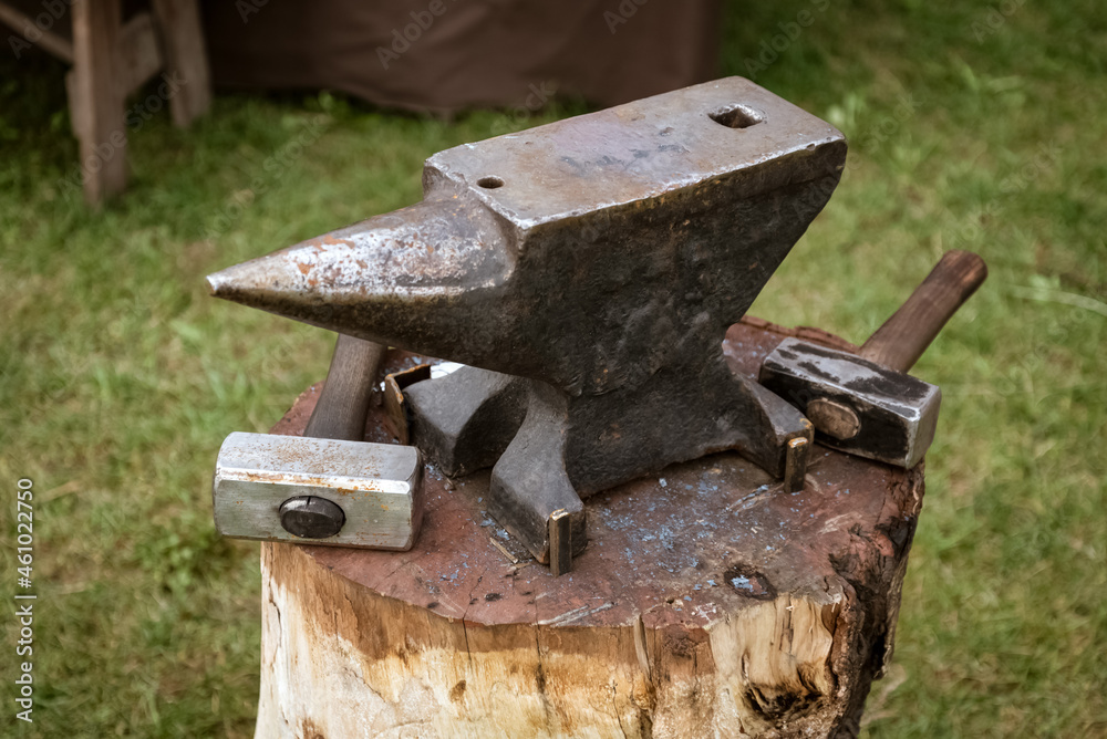 anvil and hammer on a wooden block in the forge anvil and hammer on a wooden block in the forge