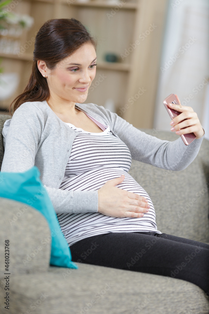pregnant woman taking selfie on smartphone