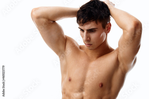 handsome guy athlete with a naked torso holds his hands behind his head 