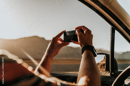A man is holding a phone while taking photos during the sunset photo