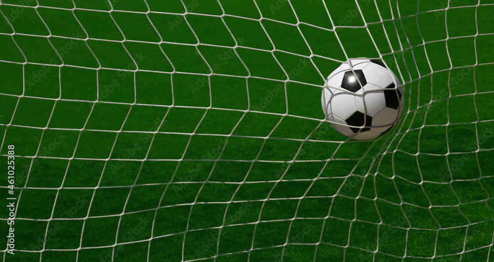 Football ball scoring in goal net over green pitch Football ball scoring in goal net over green pitch