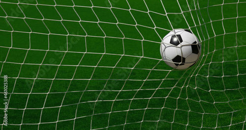 Football ball scoring in goal net over green pitch