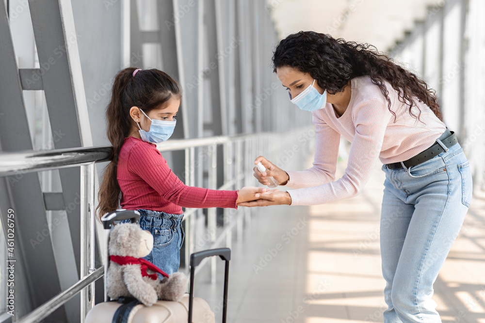 Travel Safety. Caring mom applying antibacterial spray on daughter's hands at airport - obrazy, fototapety, plakaty 