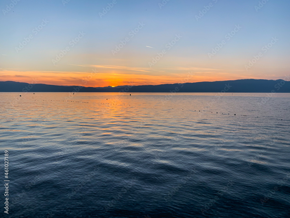 Fototapeta premium Beautiful sunset on the lake, natural colors, silhouette of the mountains background, deep blue color