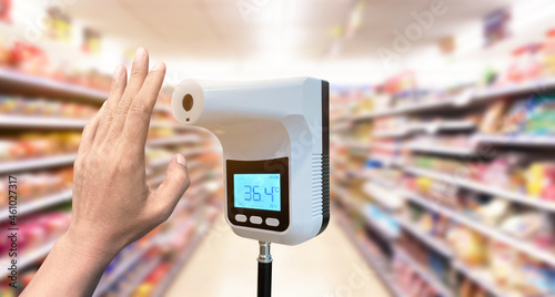 Hand customer of the front door with Digital thermometer temperature scanning machine before entering the store.