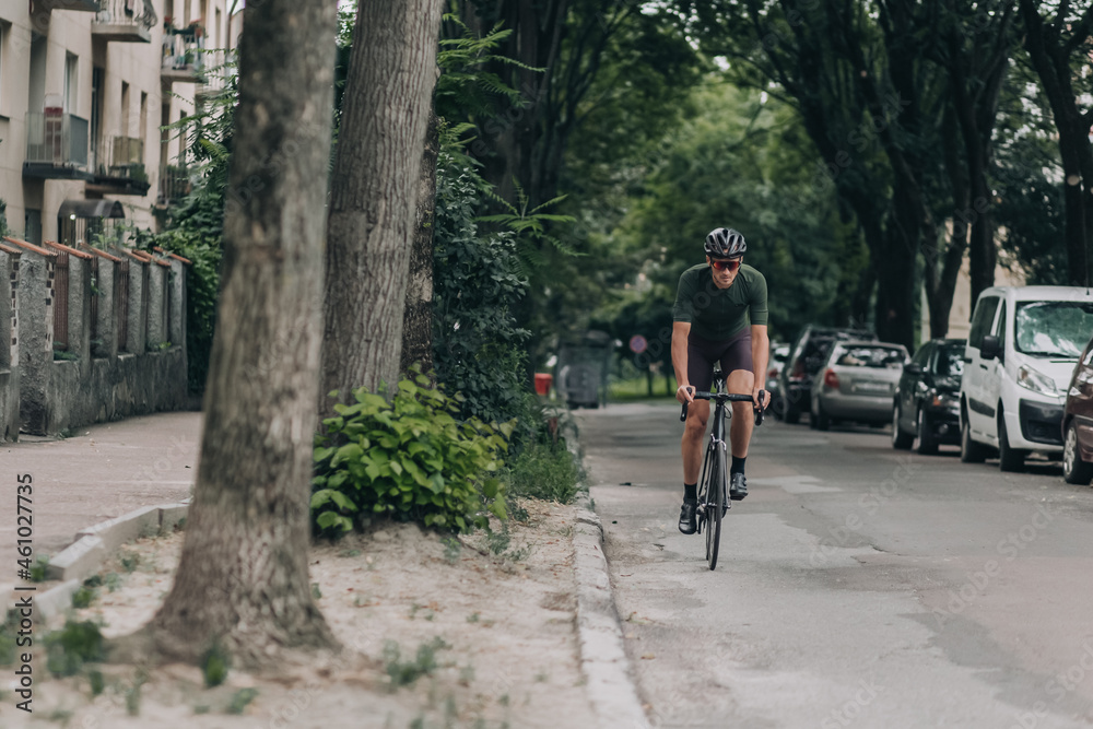 Muscular man in sportswear cycling along city street
