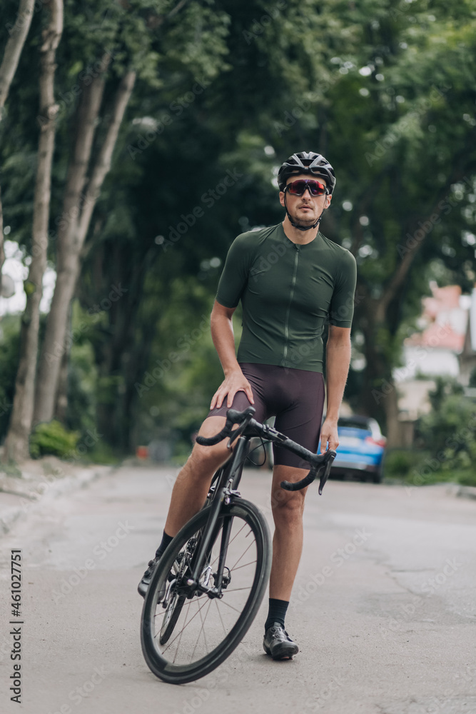 Muscular man in sport clothes sitting on bike on city street Muscular man in sport clothes sitting on bike on city street