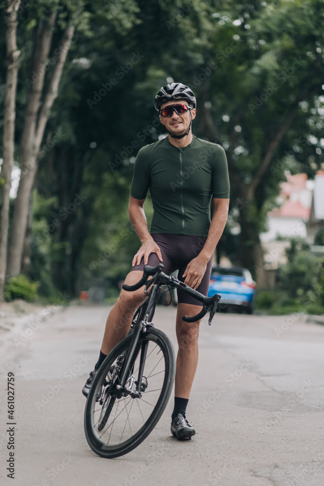 Naklejka premium Man in sportswear smiling on camera while sitting on bike