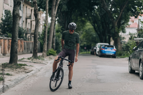 Sporty man standing with bike among empty city street