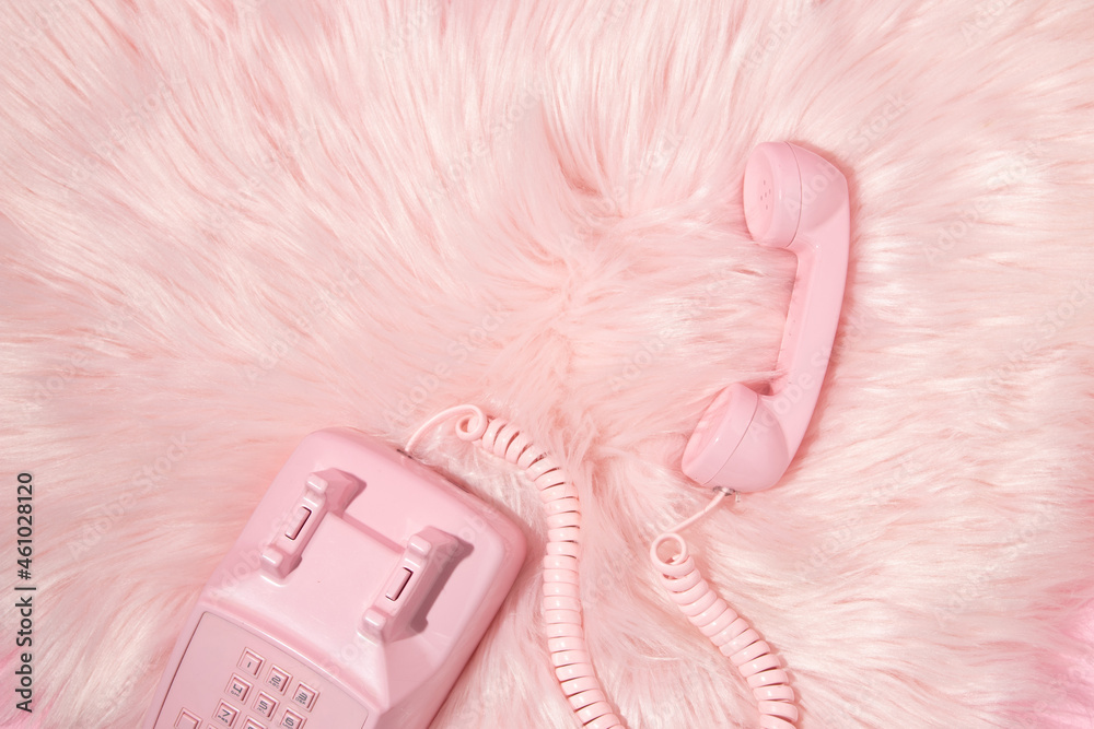 Pastel pink retro telephone handset and pastel pink faux fur background ...