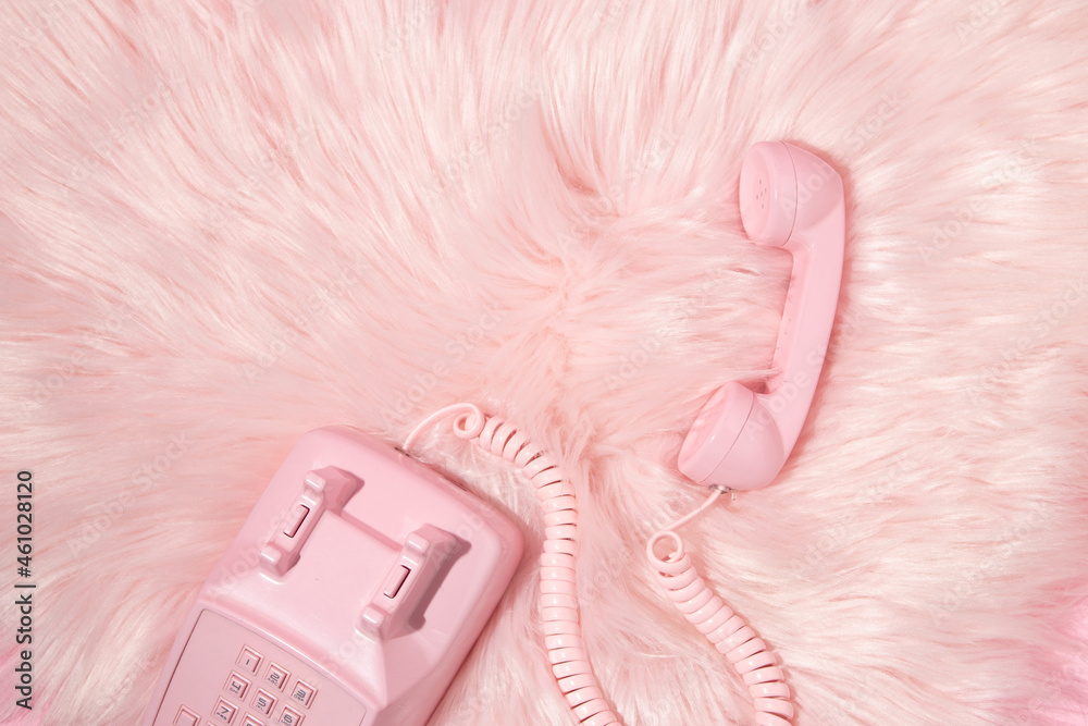Pastel pink retro telephone handset and pastel pink faux fur background