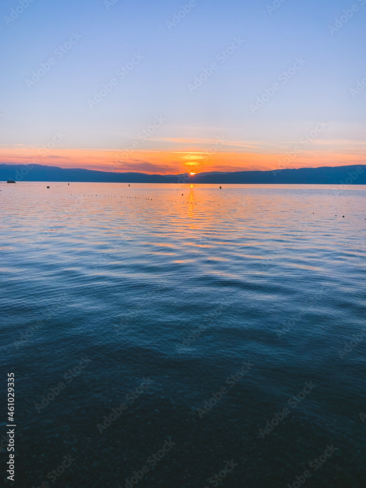 Fototapeta premium Beautiful sunset on the lake, natural colors, silhouette of the mountains background, deep blue color