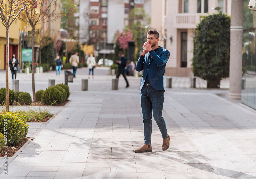 Businessman in coat talking on smartphone at urban place