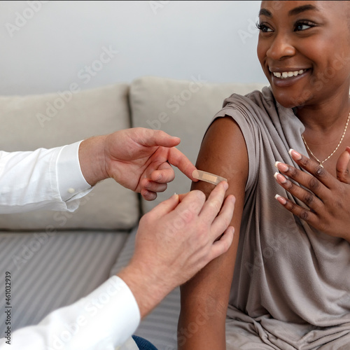 Obraz na plátne Happy patient laughs after vaccination while her doctor puts a band-aid on her arm