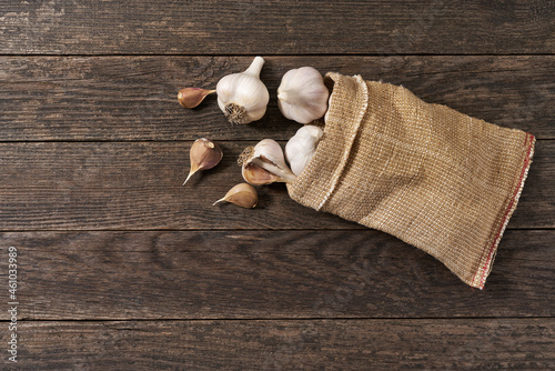 fresh garlic in a sack on a wooden table with copy space for text, top view.