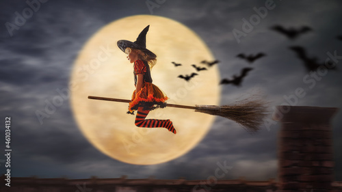 Fotografija child flies as a witch to helloween with the moon in the background