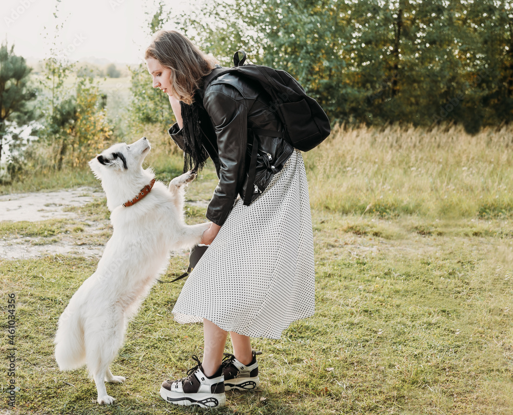 Beautiful young woman with playful young white dog having fun outdoors, full length photo. yakutian laika and her owner. lifestyle, walking in a park leisure Beautiful young woman with playful young white dog having fun outdoors, full length photo. yakutian laika and her owner. lifestyle, walking in a park leisure