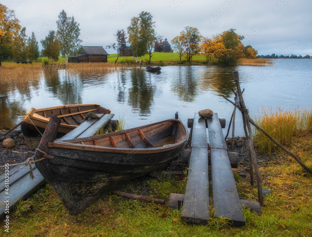 A village fishing boat made of boards in the Kizhi Museum Reserve in the north of Russia on Lake Onega with docks and a pier in golden autumn time..