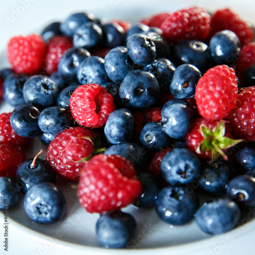 Delicious juicy ripe wild berries raspberries and blueberries in colorant. Washed berries for breakfast
