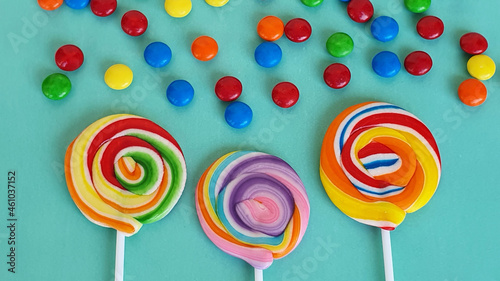Chocolate candies and colorful lollipops on green background.