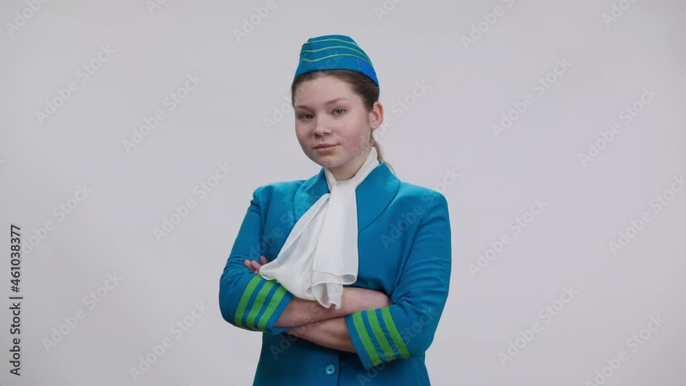 Caucasian girl in stewardess uniform crossing hands looking at camera smiling. Portrait of brunette child choosing air hostess profession posing at white background. Aviation and occupation choice Caucasian girl in stewardess uniform crossing hands looking at camera smiling. Portrait of brunette child choosing air hostess profession posing at white background. Aviation and occupation choice