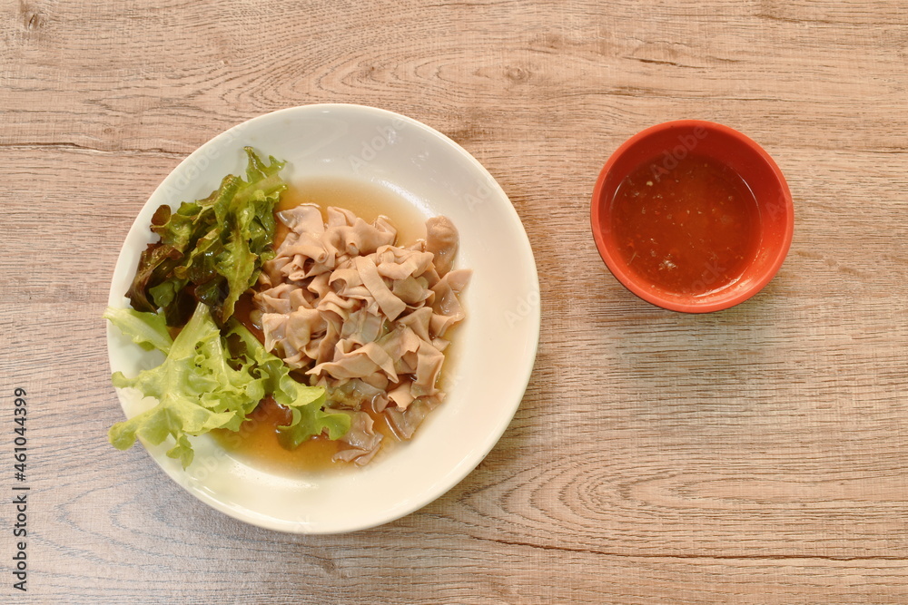 stewed duck intestine in brown soy soup on plate dipping with spicy chili sauce