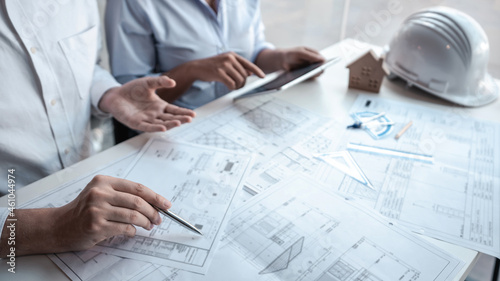 Architects or engineering team consulting and analyzing working on objects tools and construction drawings inspection planning new architectural project on blueprint and model house in modern office