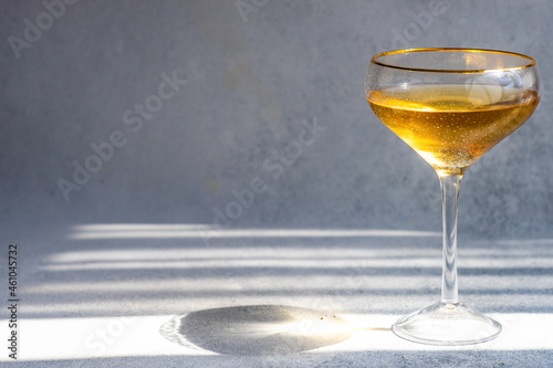 Champagne coupe of white wine on a table in sunlight