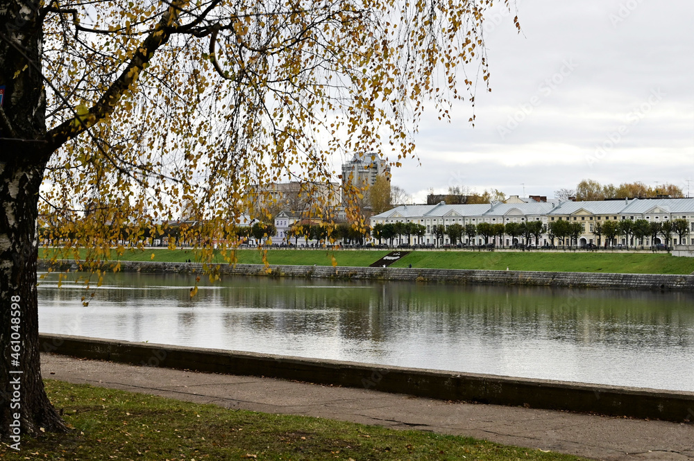 Beautiful city landscape with view of embankment with old Russian buildings in autumn. Tree with yellow leaves in foreground. Tver. Russia Beautiful city landscape with view of embankment with old Russian buildings in autumn. Tree with yellow leaves in foreground. Tver. Russia