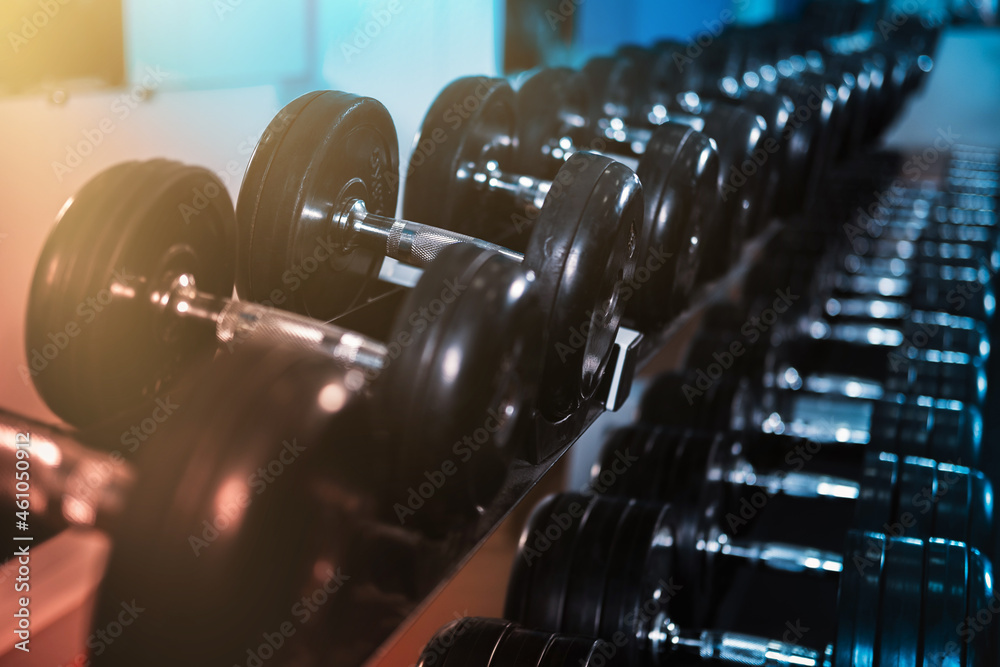 Sports background with a row of dumbbells in a dark key. 