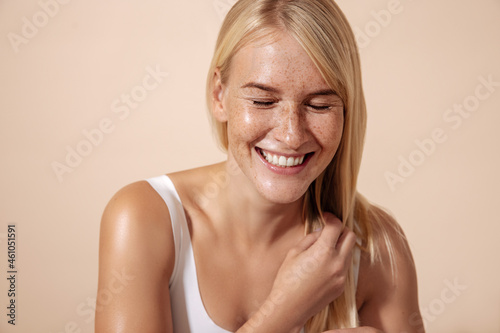 Studio shot of a happy caucasian woman adjusting her hair with closed eyes photo