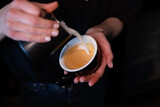 Barista pouring latte foam on coffee, espresso. creating a perfect latte art. dark colours, coffee house.