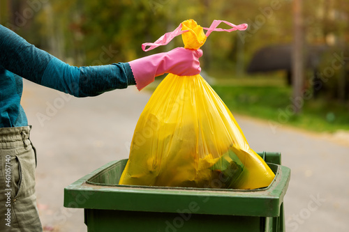 Canvas-taulu hand put a yellow plastic unsorted garbage bag into trash bin