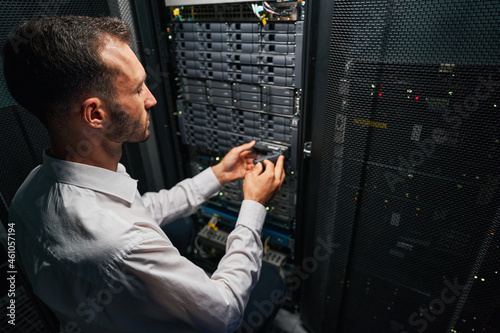Fotografia Handsome Caucasian system administrator controlling operational server rack in r