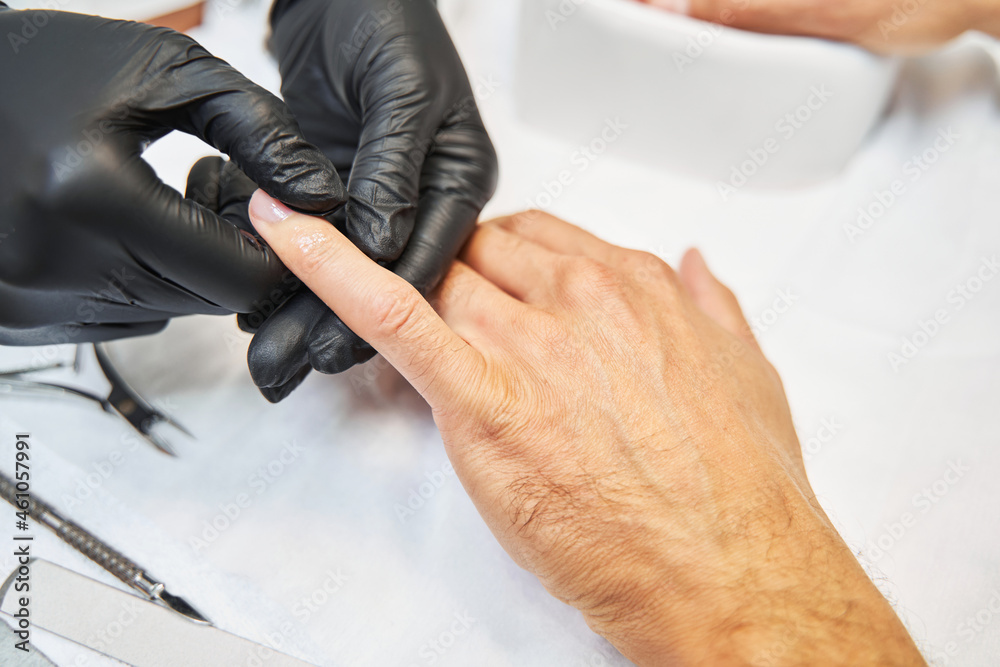 Manicure master smearing skin oil on finger