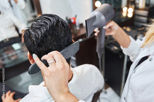 Specialist brushing hair on back of head while using hairdryer