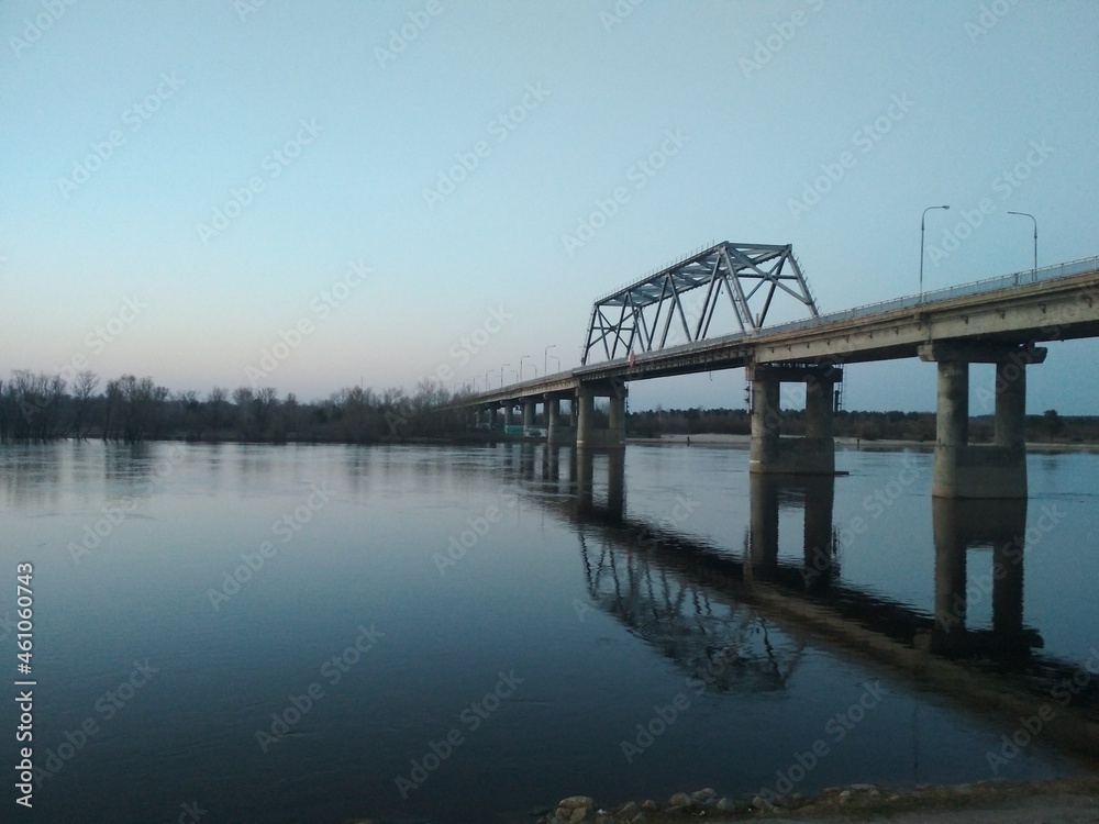 a bridge across the river in the evening with stones in the foreground. urban evening landscape