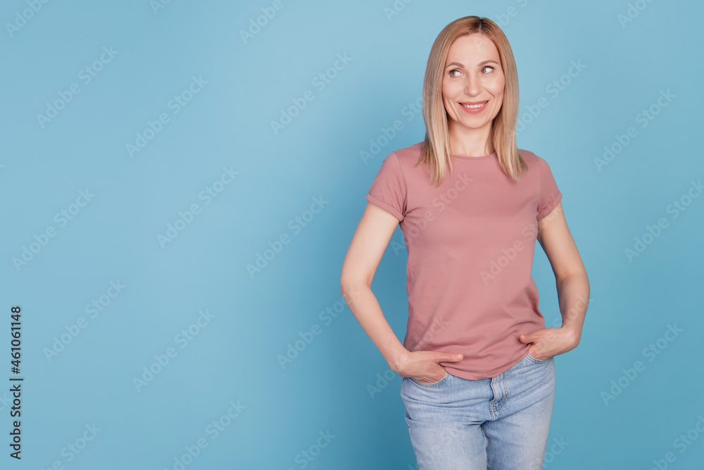 Photo of cheerful positive cute nice young woman hands in pocket look empty space isolated blue color background Photo of cheerful positive cute nice young woman hands in pocket look empty space isolated blue color background