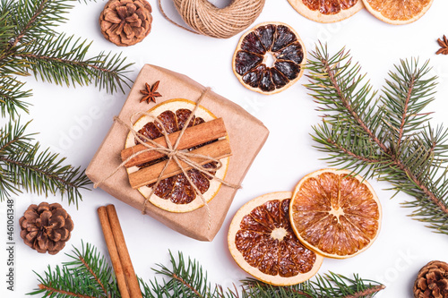 Christmas composition with handmade kraft paper gift box, dried citrus slices, cinnamon, anise, pine cones and fir tree branches, top view close up
