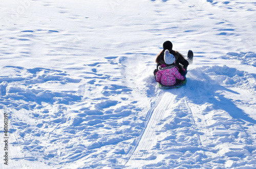 Back view of mother and daughter sledding