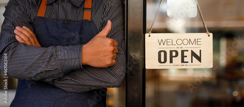 Close up of  Store owner turning open sign broad through the door glass and ready to serve. hotel service, cafe-restaurant, retail store, small business owner concept 