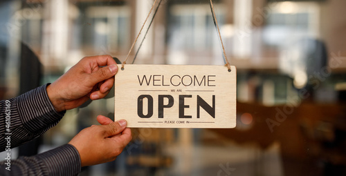 Close up of Store owner turning open sign broad through the door glass and ready to serve. hotel service, cafe-restaurant, retail store, small business owner concept 