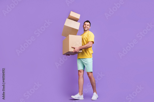Full size profile side photo of young guy happy positive smile hold cardboard delivery isolated over purple color background