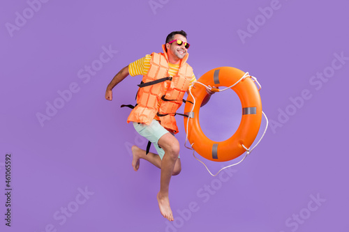 Full body photo of brunet man jump run empty space hold ring wear sunglass tip ring vest isolated on purple color background