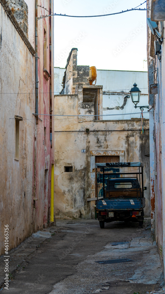 Galatina, Lecce, Puglia, Italy - August 19, 2021: views and glimpses of the historic cente. Walls with peeling plaster and a Piaggio Ape commercial vehicle to sell fruit