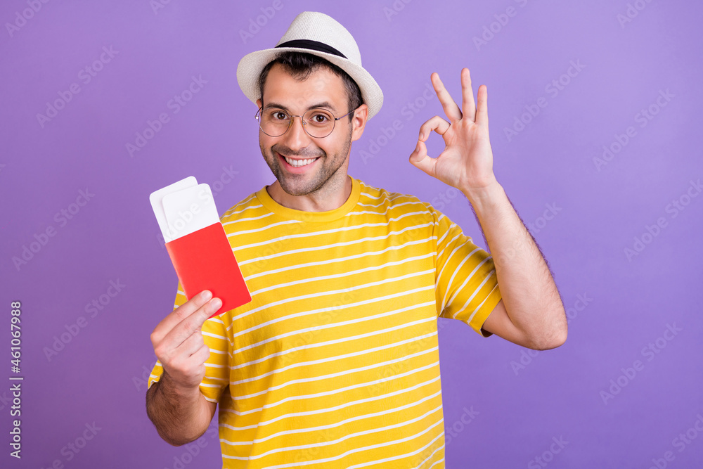 Photo of young man happy positive smile hold passport tickets trip show okay perfect sign isolated over violet color background Photo of young man happy positive smile hold passport tickets trip show okay perfect sign isolated over violet color background