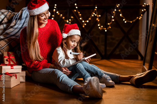 Portrait of cute girl writing letter to Santa with mom